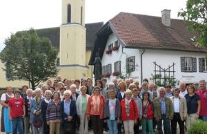 Das Foto zeigt die Ausflügler mit Reiseleiter Pfarrer Josef Rainer (vierter von rechts) vor der Pfarrkirche und dem Tourismusbüro in Piding.
